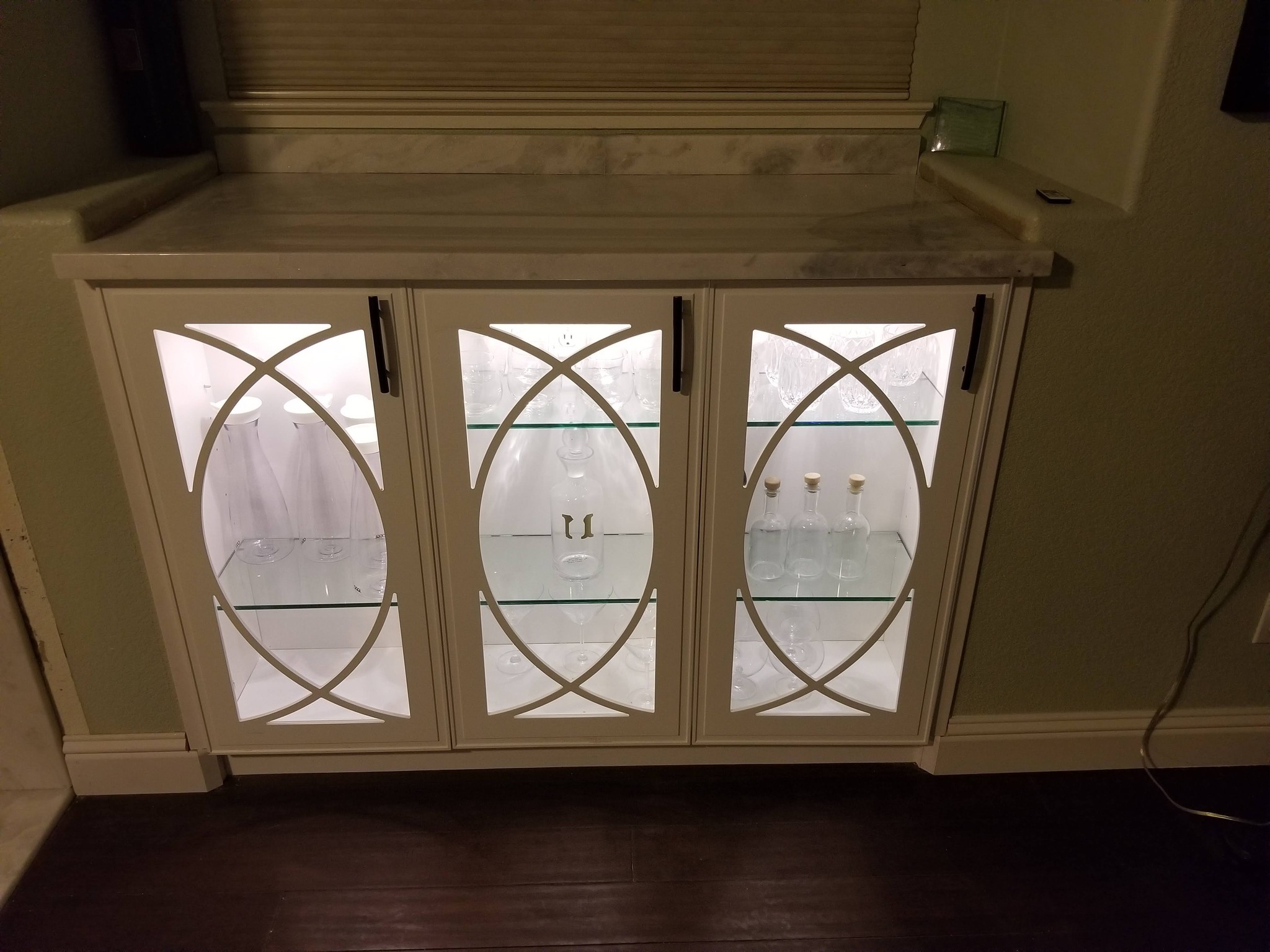 Custom built-in cabinet with illuminated shelving and marble countertop installed into a wall niche.